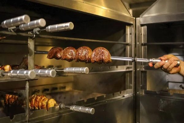 Picanha is a BBQ Steak meat grilled in charcoal. Knife cutting on skewer. Brazilian meat in a Churrascaria restaurant