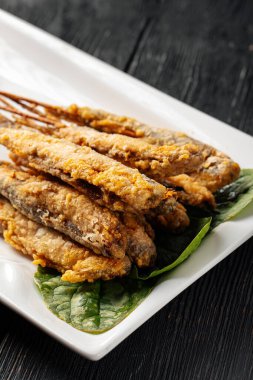Portion of gourmet asian fried capelin skewers with onion