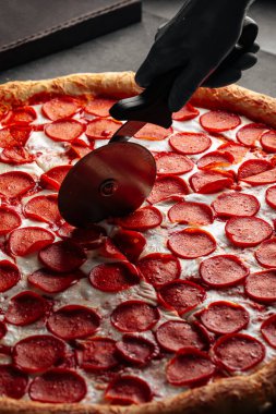 Taze pepperonili pizza dilimlenmiş özel bıçakla.