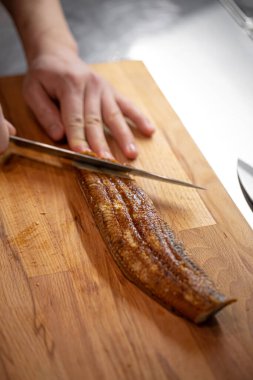 Şef Japon suşi ruloları için unagi yılanbalığını bıçakla dilimliyor.