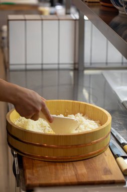 Şef ahşap kasede Japon suşisi pilavı pişiriyor.