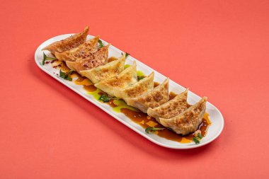 Pembe arka planda kızarmış Japon Gyoza köftesi tabağı.