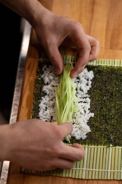 Yemek pişirir, suşi yapar, salatalıkla.