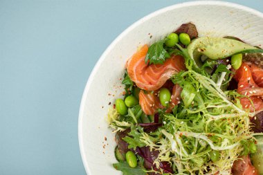 Mavi arka planda somonlu taze gurme salatası.