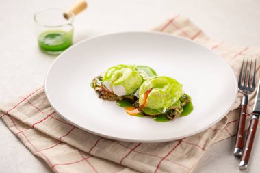 Haşlanmış yumurta ve yeşil soslu gurme kahvaltısı.