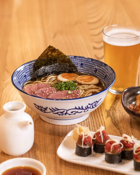 Table with japanese lunch dishes ramen sushi and beer