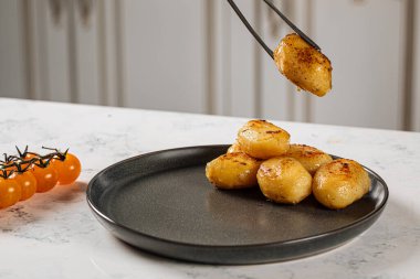 Patatesleri maşayla tabağa koymak.