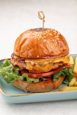 Hafif arka planda patates kızartması ve sığır etli burger.