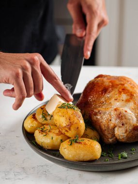 Şef bütün tavuğu patatesle iştah açıcı hazırlıyor.
