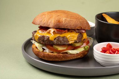 Yeşil arka planda patates dilimleri olan hamburger porsiyonu.