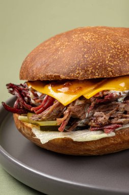 Yeşil arka planda patates dilimleri olan göğüs eti burgeri.