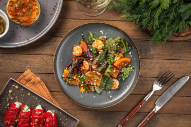 Porsiyon salata, hurma ve ahşap servis masasında karides.