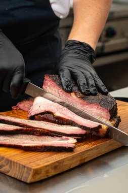 Şef mutfakta füme sığır eti dilimliyor.