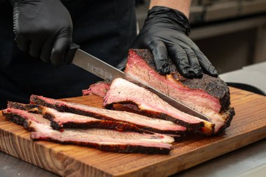 Şef mutfakta füme sığır eti dilimliyor.