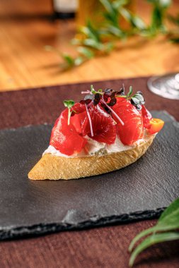 Siyah tabakta kırmızı balıklı gurme bruschetta.
