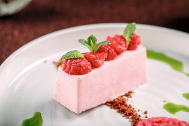 Bir porsiyon ahududu kremalı tatlı ve dondurma.