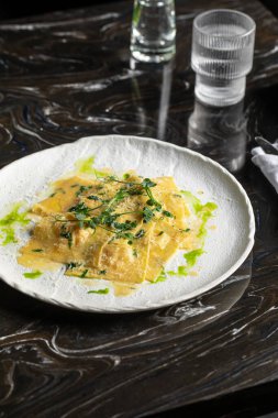 Soslu ve yeşil yağlı İtalyan mantısı.