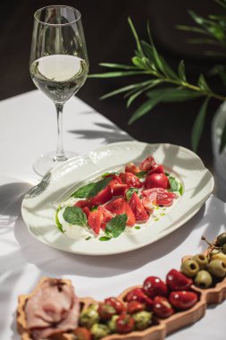 Restoran teras masasında şarap, domates ve tabakla servis edilir.