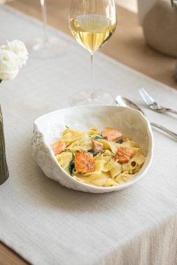 Izgara somonlu kremalı makarna ve zarif sofrada beyaz şarap.