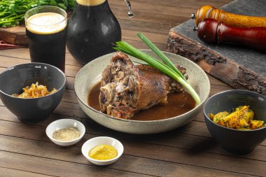 Kızarmış domuz budu, lahana sosu ve ahşap masada patates.