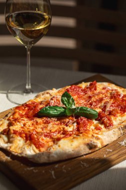Tahta tahtada domates, peynir ve fesleğenli Pinsa margherita ve şarap.