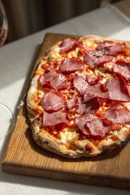 Ahşap tahtada kurutulmuş et ve peynirli Pinsa.