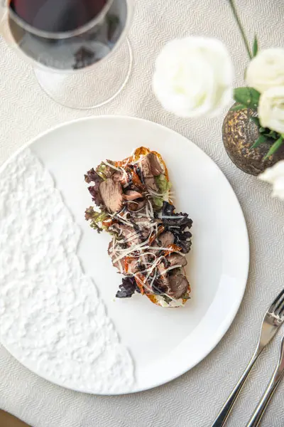 Rosto, biftek ve beyaz tabakta yeşil şarap.