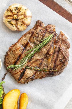 Biberiye sarımsaklı ızgara biftek ve servis masasında patates kaması.