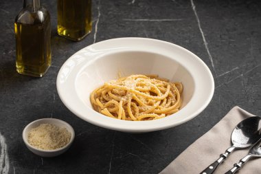 Siyah masada beyaz kasede servis edilen parmesan peynirli spagetti.