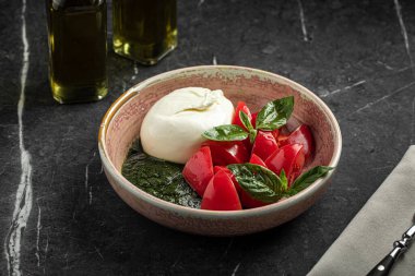 Seramik kasede burrata, domates ve fesleğen yapraklı taze Caprese salatası.
