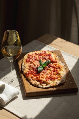 Tahta tahtada domates, peynir ve fesleğenli Pinsa margherita ve şarap.