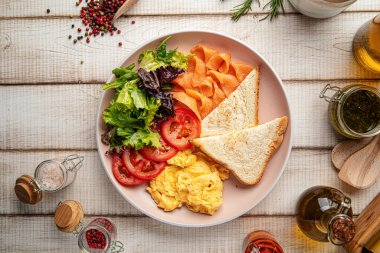 Yağda yumurta, tost, füme somon ve taze sebzeli sağlıklı kahvaltı tabağı.