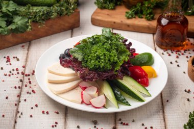 Taze sebze ve peynir tabağı ve beyaz tabakta otlar.