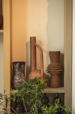 Sıcak iç ışıkta ahşap rafta kırsal seramik vazolar