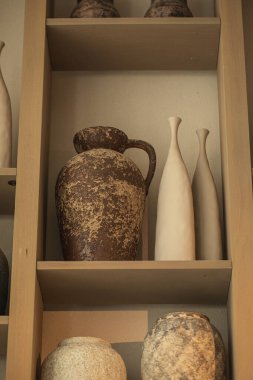 Sıcak iç ışıkta ahşap rafta kırsal seramik vazolar