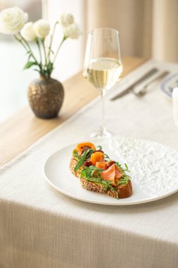 Somon bruschetta roka ve susamlı ekmek. Şık bir sofrada şarapla servis ediliyor.