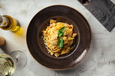 Klasik İtalyan carbonara makarnası, domuz pastırması, parmesan ve fesleğen, koyu bir tabakta servis edilir.