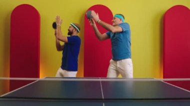 Ping pong oynamaya başlamadan önce heyecanlı dans eden yakışıklı iki adam kameranın önünde raketi ellerinde tutuyorlar. ARRI Alexa Mini 'de çekilen