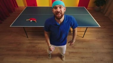 Masa tenisi maçını kazandıktan sonra çok heyecanlanan ve mutlu olan genç adam kameranın önünde spor ve sağlıklı yaşam tarzının önünde dans eder ve çok hızlı hareket eder. 4k