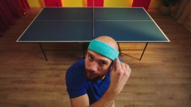 Üniformalı iyi görünümlü masa tenisi oyuncusu kameraya yaklaş ve oyuna başlamak için hazır ol. Gülümsüyor ve enerjiden heyecanlanıyor. ARRI Alexa Mini 'de çekilen