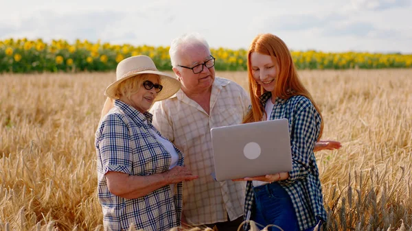 Family business concept grandparents farmers and their beautiful niece in the middle of a large wheat field happy hugging each other.