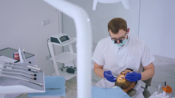 歯科医院のコンセプト歯科医は この患者が歯医者の椅子に横たわっているために歯科器具を使用して患者の歯の治療を行っています — ストック動画