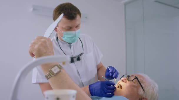 老人のための口腔ケア治療は 彼が歯医者の椅子に横たわっていた歯科医を訪問し 治療のための医療機器を使用して医師を検査するために来ました Arriで撃たれた — ストック動画