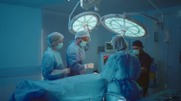 Три Медичні Хірурги Скрабах Один Стоїть Чолі Пацієнта Темно Синіх — стокове відео