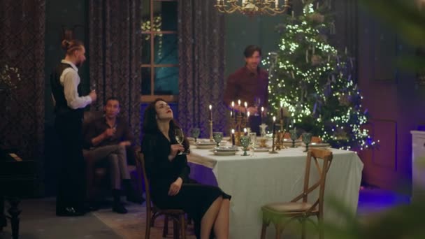 在一个美妙的圣诞气氛中 有漂亮的装饰品记录着一群人坐在餐桌旁庆祝圣诞节的视频 一个男人坐在她旁边 — 图库视频影像