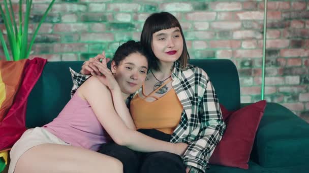 カメラの前では ソファーに座っているレズビアンのカップルの女性たちが Lgbtの自由と平等というお互いの概念を抱き合ってテレビを見ています Arriアレクサミニで撮影 — ストック動画