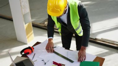 In front of the camera taking video of a man architect analysing and make some measurements of the plan of construction he using a pencil to make the notes. 4k