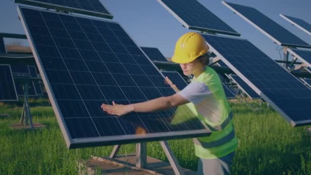 在现代光伏太阳能农场 戴着安全帽的年轻女性生态工程师检查太阳能电池板是否干净 — 图库视频影像