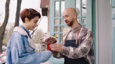 Modern and cute floral shop outside the shop the entrepreneur and owner of the shop have a discussion with the customer lady how to take care after the plants from the pot. Shot on ARRI Alexa Mini