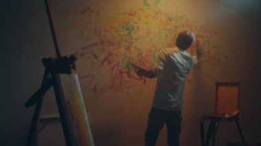 Contemporary and modern artwork artist holding his colour palette and add with fingers the colour on the wall. 4k